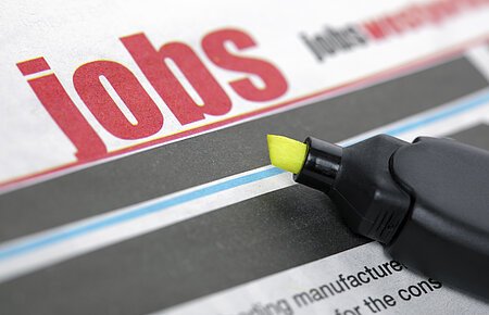 Stellenangebote Zeitungsseite mit dem Wort "Jobs" in großen roten Buchstaben und ein gelber Textmarker liegt auf der Zeitung.