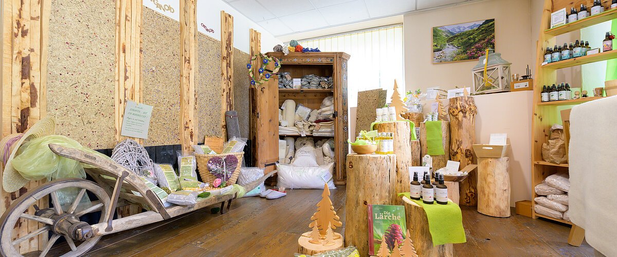 Innenraum eines Verkaufsraums mit Holzstämmen als Präsentationsflächen und Naturprodukten auf Holzboden.