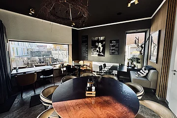 Innenraum eines Cafés mit runden und eckigen Tischen, Stühlen und großem Fenster mit Blick nach draußen