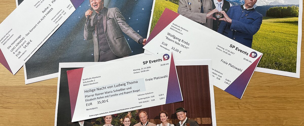 Drei Konzertkarten von SP Events liegen auf Fotos von Musikern in traditioneller und moderner Kleidung auf einem Holztisch. Kartenvorverkauf für die nächsten Veranstaltungen in Monheim