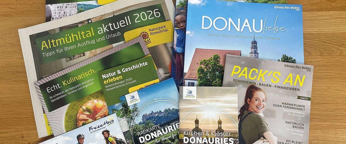 Mehrere Broschüren und Flyer zu Urlaub, Naturpark Altmühltal und Donau-Ries auf Holztisch liegend. Neuauflagen verschiedener Flyer und Broschüren in der Tourist-Information zur Abholung
