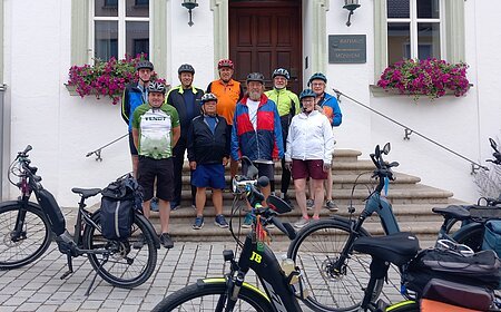 Neun Radfahrer mit Helmen stehen vor dem Rathaus Monheim, davor sind mehrere E-Bikes abgestellt. Auftakt zum Stadtradeln 2026 in Monheim
