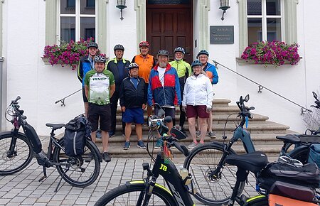 Neun Radfahrer mit Helmen stehen vor dem Rathaus Monheim, davor sind mehrere E-Bikes abgestellt. Auftakt zum Stadtradeln 2026 in Monheim