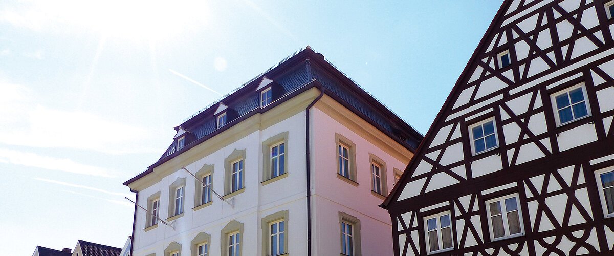 Straßenansicht der Monheimer Innenstadt: Im Vordergrund das Rathaus der Stadt Monheim, mit weiteren mehreren Gebäuden, darunter ein Fachwerkhaus, das man Schindlerhaus nennt.