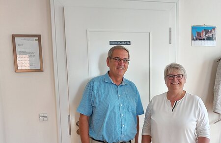 Neuer Feldgeschworener für den Stadtteil Flotzheim Mann und Frau stehen vor einer weißen Tür in einem Raum mit Holzboden und Pflanzen. Erste Bürgermeisterin Anita Ferber bei der Vereidigung des neuen Feldgeschworenen für den Stadtteil Flotzheim Hermann Färber
